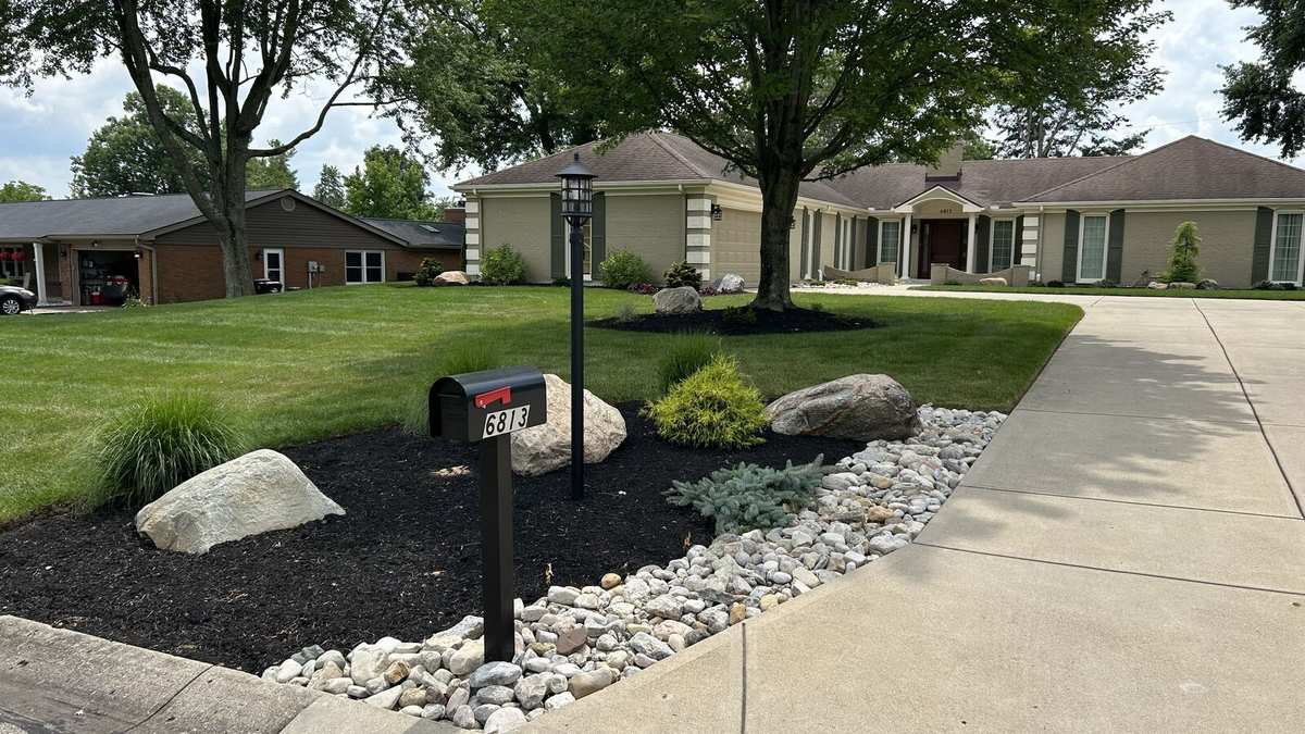 Finished driveway bed with boulders, river rock and plantings