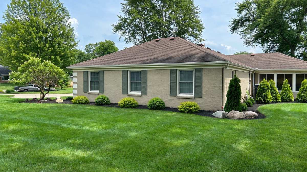 Side of the house after: new foundation beds with evergreens and boulders
